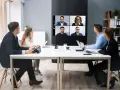 Une équipe en visioconférence, illustrant le futur du travail. Des collègues échangent à distance, connectés via un écran mural.
