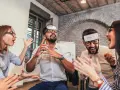 Des employés s'amusent lors d'un jeu d'entreprise exemple, devinant des mots inscrits sur des bandeaux.