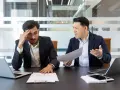 Un homme en colère crie sur son collègue, qui a l'air stressé. Une scène de **management toxique** dans un bureau.