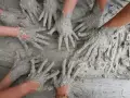 Des mains couvertes de boue s'entremêlent, une image parfaite pour une idée challenge entreprise axée sur la collaboration et la créativité.