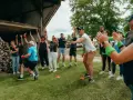 Des participants enthousiastes s'amusent lors d'un événement de team building jeux olympiques, bras levés et souriants.