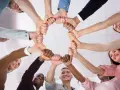 Un cercle de mains jointes symbolise la dynamique d'équipe et la solidarité. Des sourires illuminent les visages, reflétant la joie du travail collaboratif.