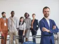 Un homme d'affaires souriant, qui semble avoir du charisme, pose devant son équipe.
