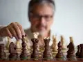 Un homme réfléchit, une pièce d'échecs à la main. Il faut avoir un esprit critique pour anticiper chaque mouvement.