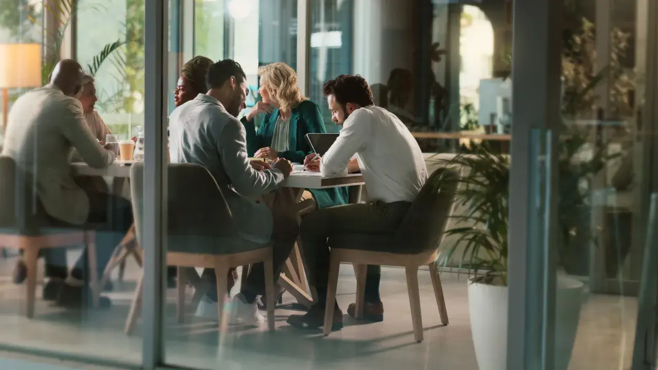 Des employés discutent autour d'une table, mais chacun semble travailler dans son coin, comme s'ils étaient en train de travailler en silo.