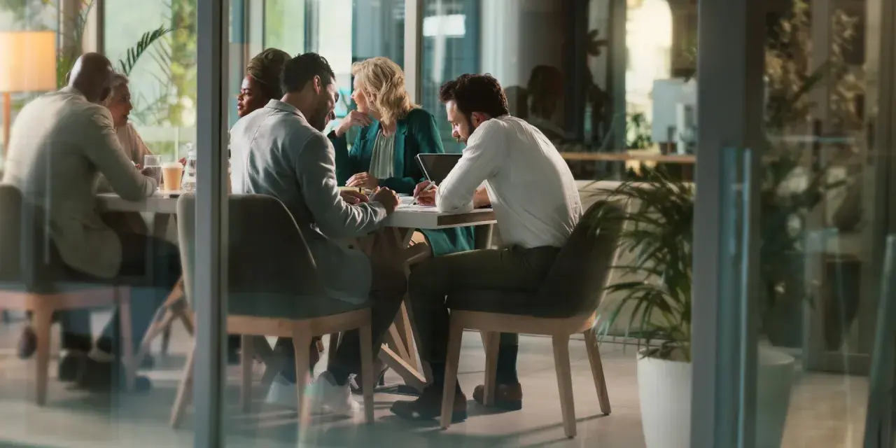 Des employés discutent autour d'une table, mais chacun semble travailler dans son coin, comme s'ils étaient en train de travailler en silo.