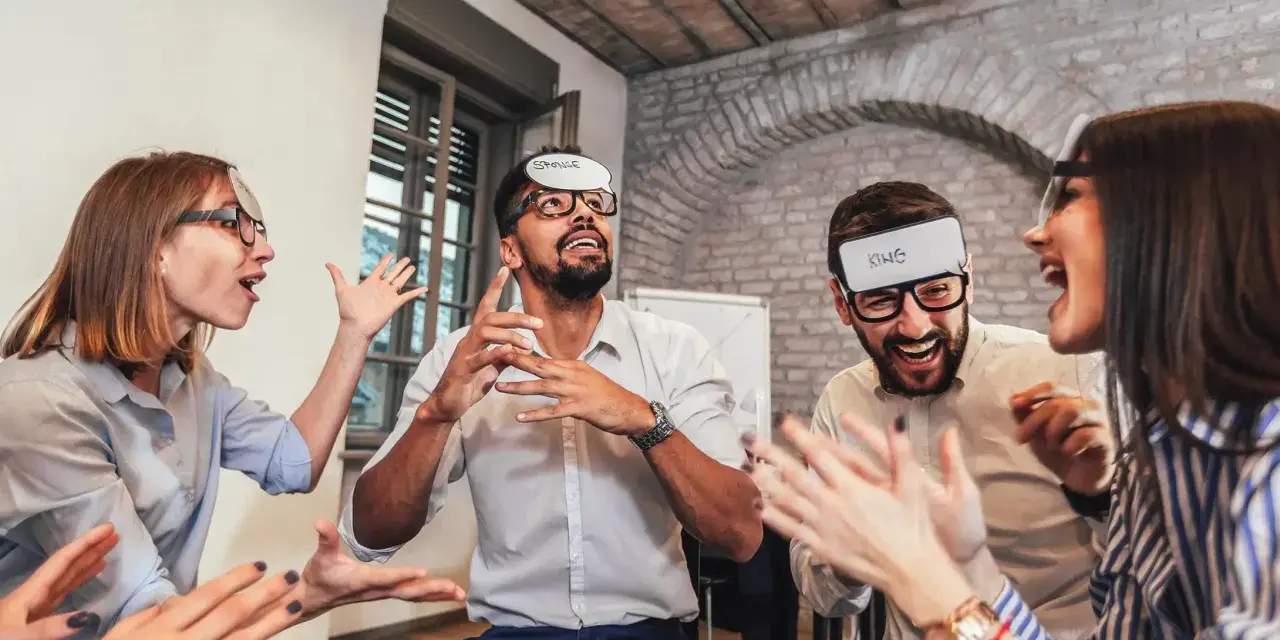 Des employés s'amusent lors d'un jeu d'entreprise exemple, devinant des mots inscrits sur des bandeaux.