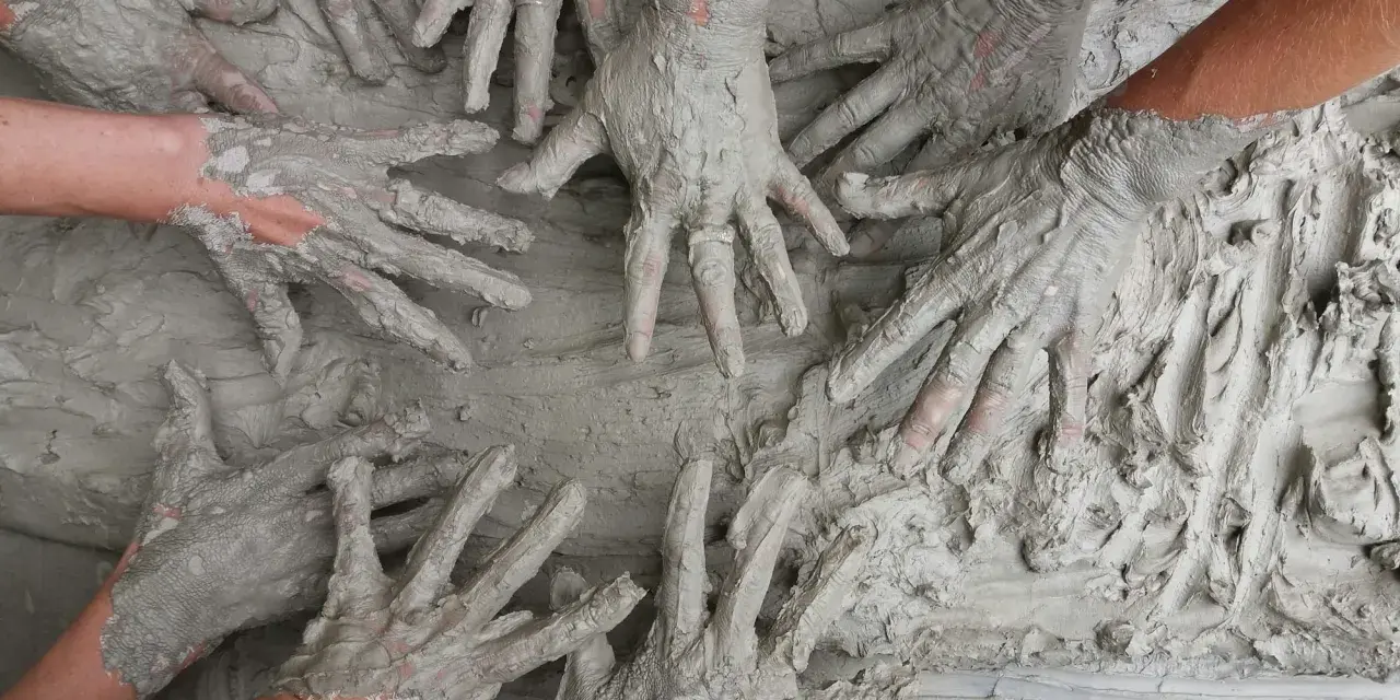 Des mains couvertes de boue s'entremêlent, une image parfaite pour une idée challenge entreprise axée sur la collaboration et la créativité.
