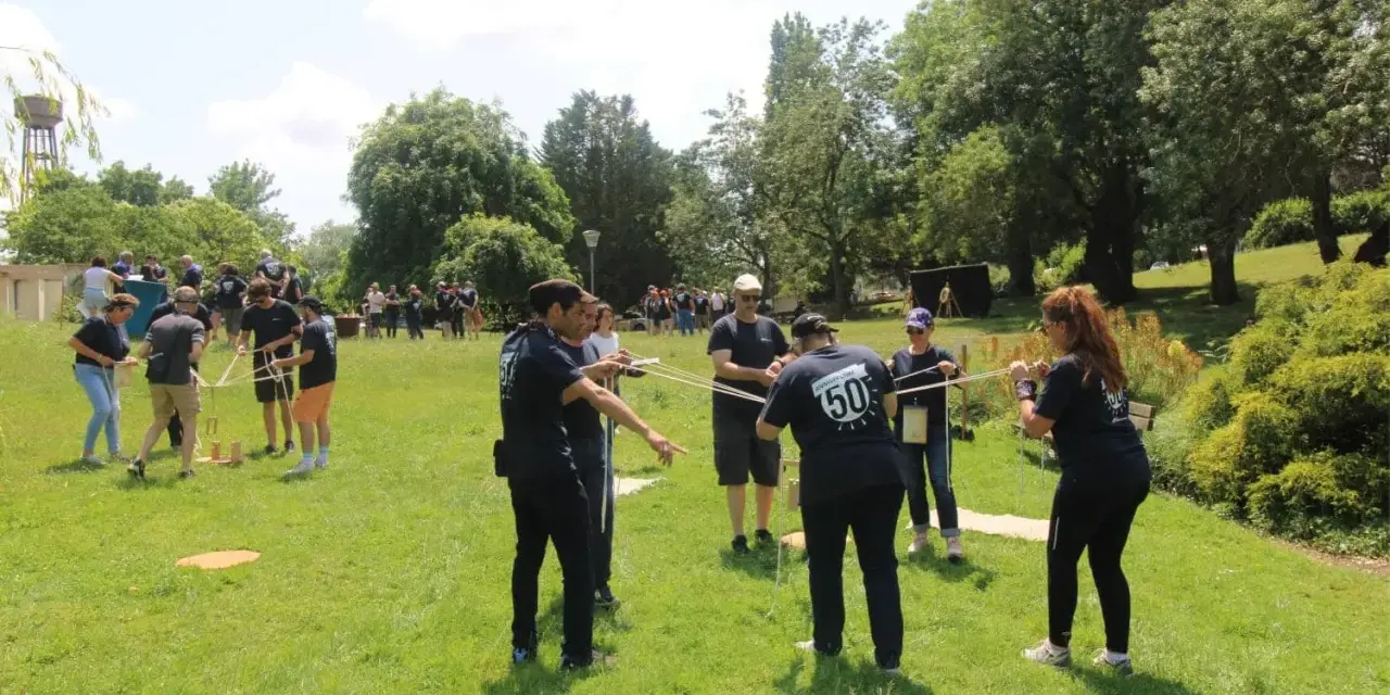 Des personnes participent à une activité de plein air, une idée de challenge sportif, en manipulant des cordes et des structures en bois.