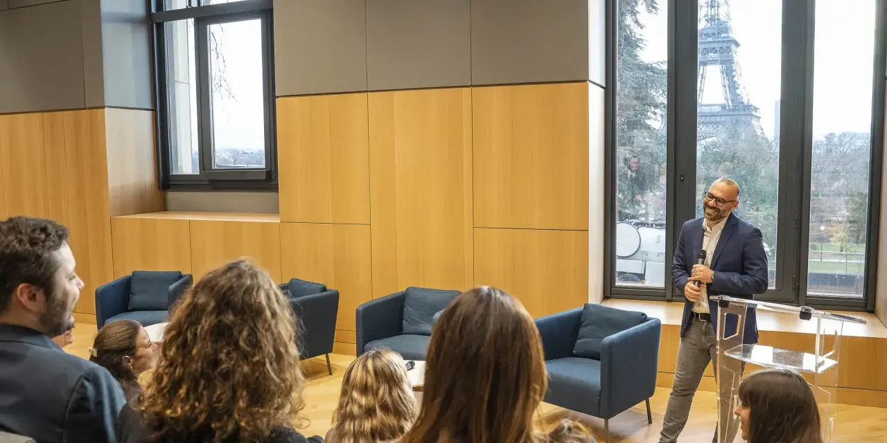 Un homme présente un programme séminaire entreprise à Paris, avec la Tour Eiffel en arrière-plan.