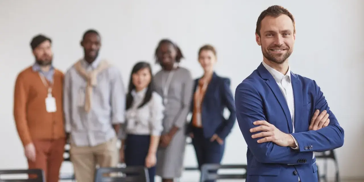 Un homme d'affaires souriant, qui semble avoir du charisme, pose devant son équipe.