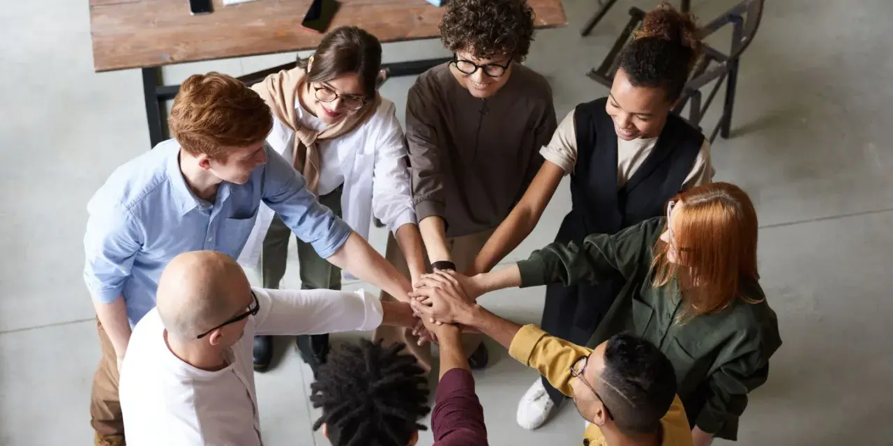 Une équipe soudée après une conférence en entreprise, mains jointes au centre, symbolisant la collaboration et le succès.