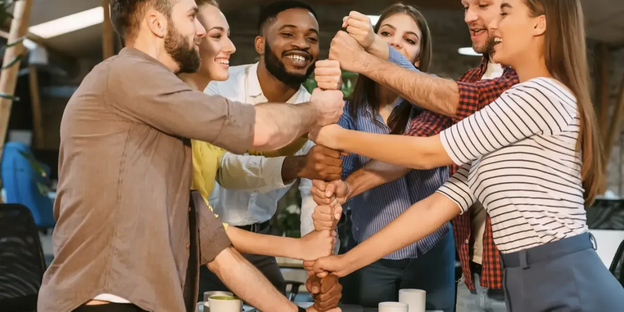 Une équipe soudée célèbre un événement team building, unissant leurs poings pour symboliser la force collective et la réussite.