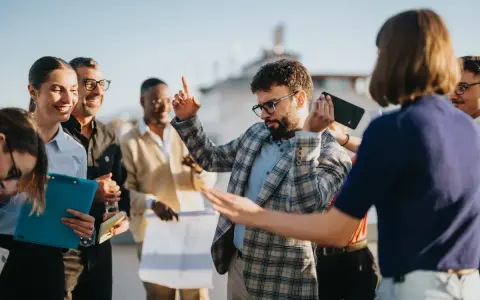Une équipe célèbre sa journée du personnel avec joie. Un homme danse, d'autres sourient, certains tiennent des documents.
