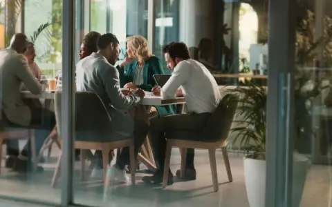 Des employés discutent autour d'une table, mais chacun semble travailler dans son coin, comme s'ils étaient en train de travailler en silo.