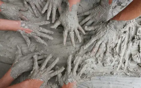 Des mains couvertes de boue s'entremêlent, une image parfaite pour une idée challenge entreprise axée sur la collaboration et la créativité.