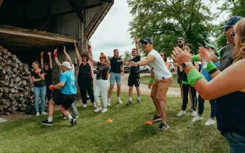 Des participants enthousiastes s'amusent lors d'un événement de team building jeux olympiques, bras levés et souriants.