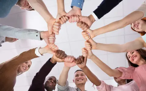 Un cercle de mains jointes symbolise la dynamique d'équipe et la solidarité. Des sourires illuminent les visages, reflétant la joie du travail collaboratif.