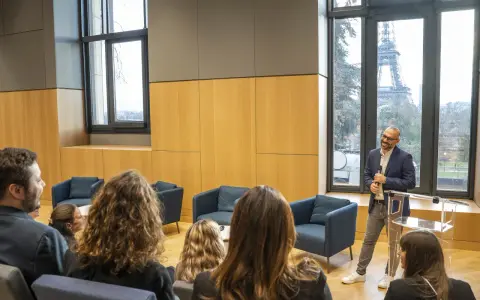 Un homme présente un programme séminaire entreprise à Paris, avec la Tour Eiffel en arrière-plan.