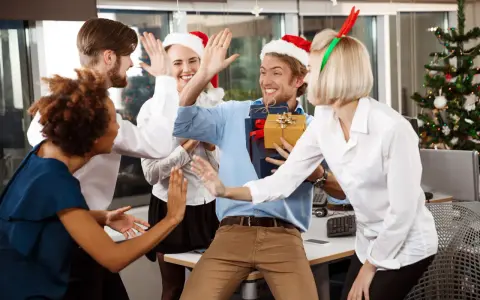Une équipe célèbre Noël en entreprise, avec des pères Noël et des bois de renne. Ils s'amusent et échangent des cadeaux, un vrai challenge de fin d'année réussi !