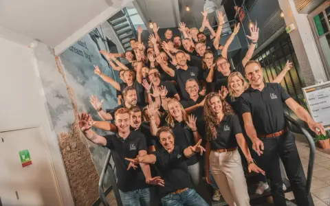 Une équipe souriante et joyeuse, unie pour un moment de **team building gratuit**. Ils montent les escaliers, bras levés, prêts à relever de nouveaux défis.