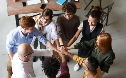 Une équipe soudée après une conférence en entreprise, mains jointes au centre, symbolisant la collaboration et le succès.
