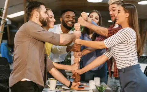 Une équipe soudée célèbre un événement team building, unissant leurs poings pour symboliser la force collective et la réussite.