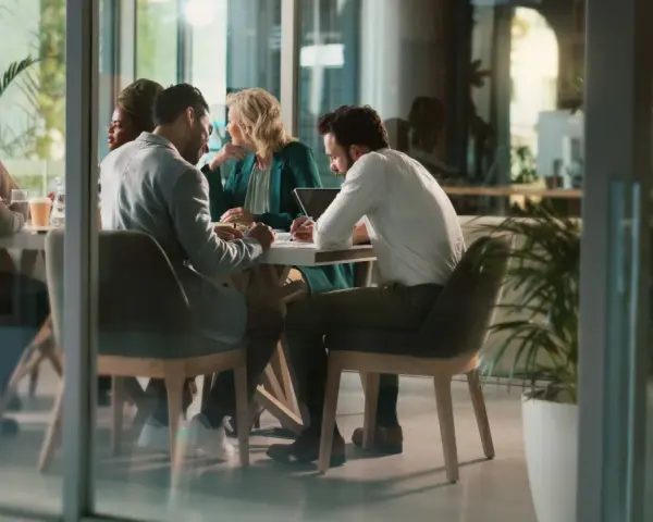 Des employés discutent autour d'une table, mais chacun semble travailler dans son coin, comme s'ils étaient en train de travailler en silo.