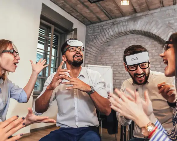 Des employés s'amusent lors d'un jeu d'entreprise exemple, devinant des mots inscrits sur des bandeaux.