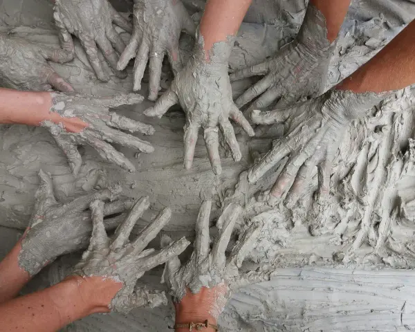 Des mains couvertes de boue s'entremêlent, une image parfaite pour une idée challenge entreprise axée sur la collaboration et la créativité.