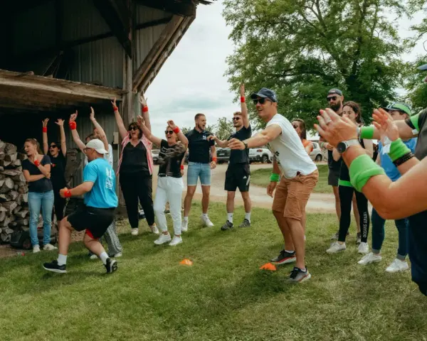 Des participants enthousiastes s'amusent lors d'un événement de team building jeux olympiques, bras levés et souriants.