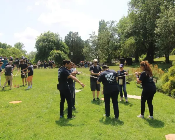 Des personnes participent à une activité de plein air, une idée de challenge sportif, en manipulant des cordes et des structures en bois.