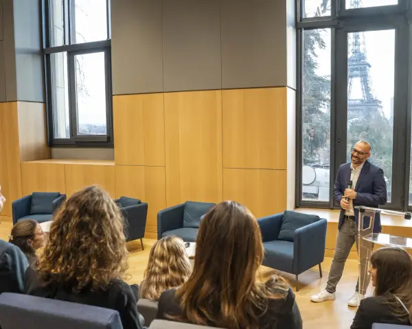 Un homme présente un programme séminaire entreprise à Paris, avec la Tour Eiffel en arrière-plan.