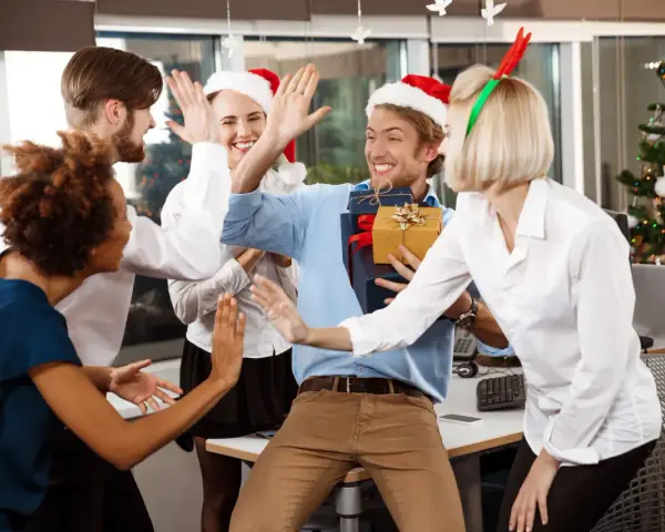 Une équipe célèbre Noël en entreprise, avec des pères Noël et des bois de renne. Ils s'amusent et échangent des cadeaux, un vrai challenge de fin d'année réussi !