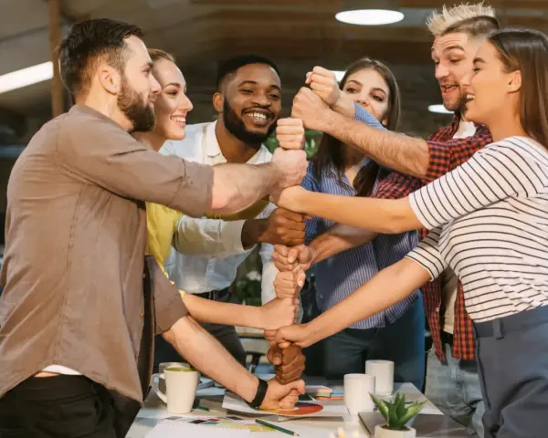 Une équipe soudée célèbre un événement team building, unissant leurs poings pour symboliser la force collective et la réussite.