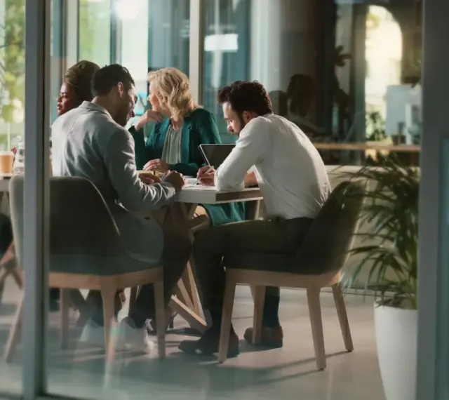 Des employés discutent autour d'une table, mais chacun semble travailler dans son coin, comme s'ils étaient en train de travailler en silo.