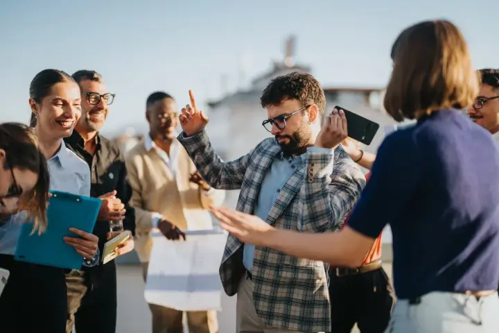 Une équipe célèbre sa journée du personnel avec joie. Un homme danse, d'autres sourient, certains tiennent des documents.
