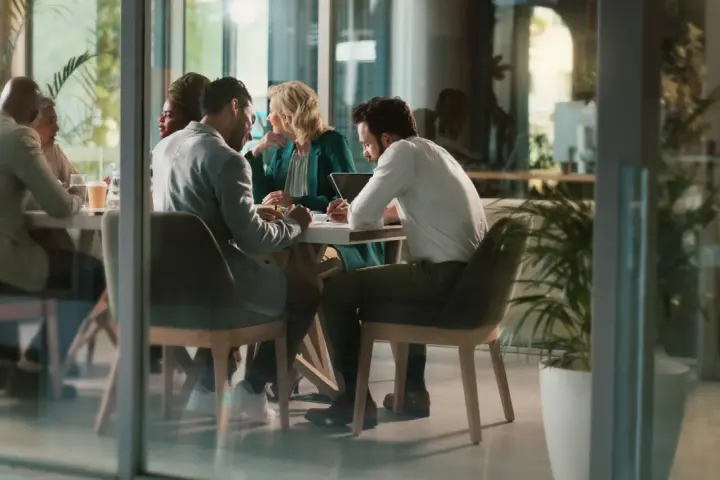 Des employés discutent autour d'une table, mais chacun semble travailler dans son coin, comme s'ils étaient en train de travailler en silo.