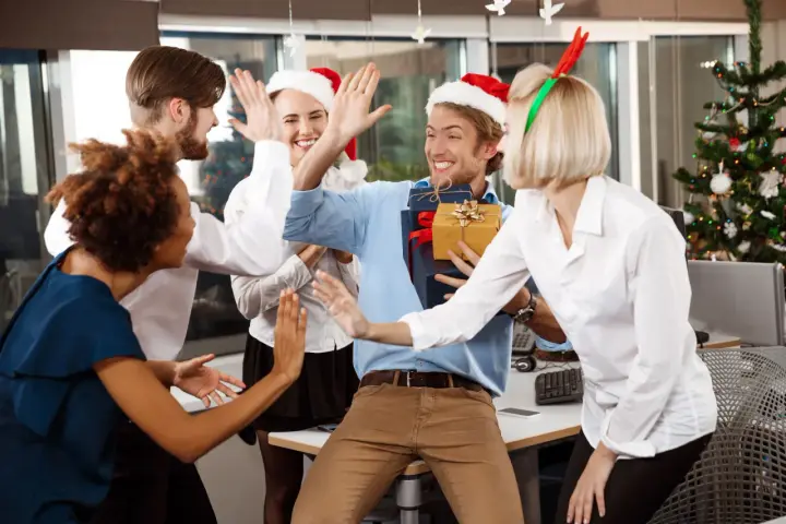 Une équipe célèbre Noël en entreprise, avec des pères Noël et des bois de renne. Ils s'amusent et échangent des cadeaux, un vrai challenge de fin d'année réussi !