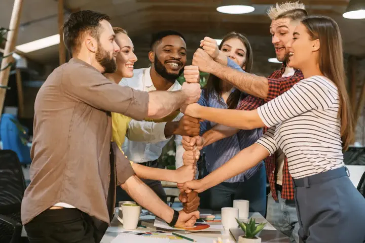 Une équipe soudée célèbre un événement team building, unissant leurs poings pour symboliser la force collective et la réussite.