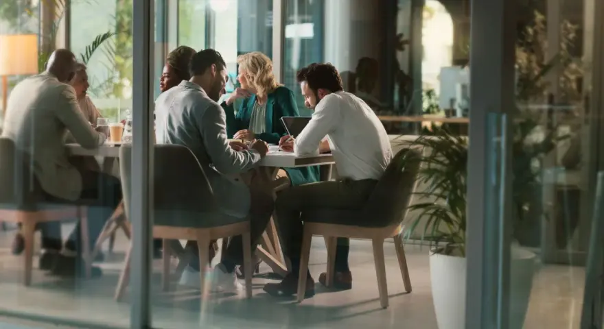 Des employés discutent autour d'une table, mais chacun semble travailler dans son coin, comme s'ils étaient en train de travailler en silo.