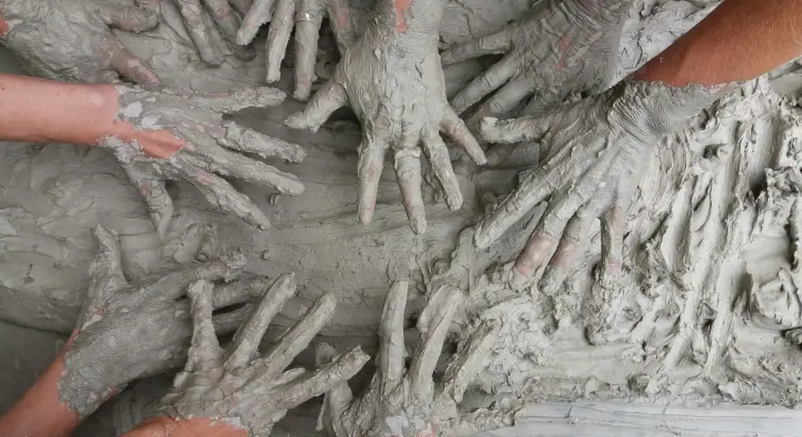 Des mains couvertes de boue s'entremêlent, une image parfaite pour une idée challenge entreprise axée sur la collaboration et la créativité.