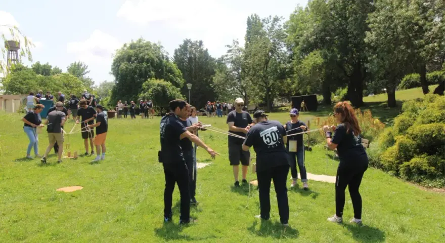 Des personnes participent à une activité de plein air, une idée de challenge sportif, en manipulant des cordes et des structures en bois.