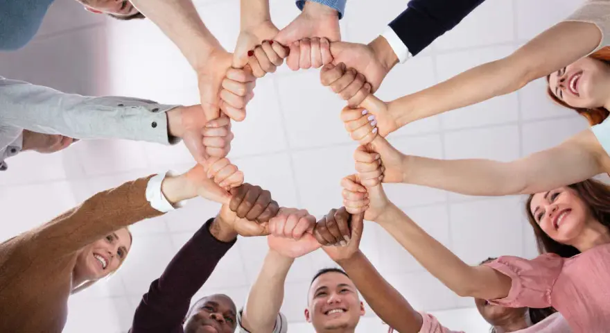 Un cercle de mains jointes symbolise la dynamique d'équipe et la solidarité. Des sourires illuminent les visages, reflétant la joie du travail collaboratif.