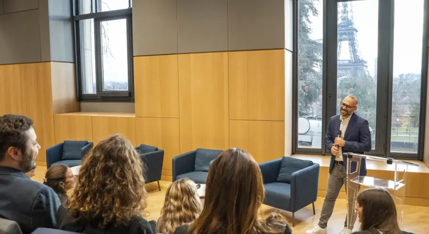 Un homme présente un programme séminaire entreprise à Paris, avec la Tour Eiffel en arrière-plan.