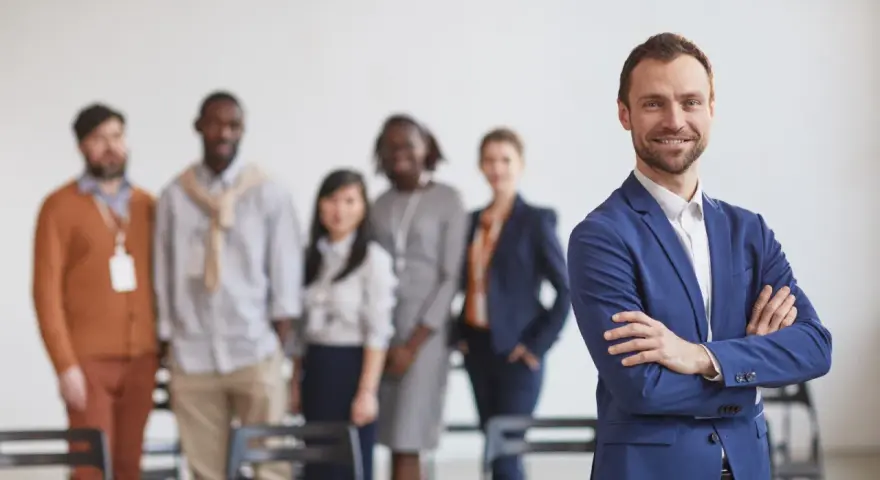 Un homme d'affaires souriant, qui semble avoir du charisme, pose devant son équipe.