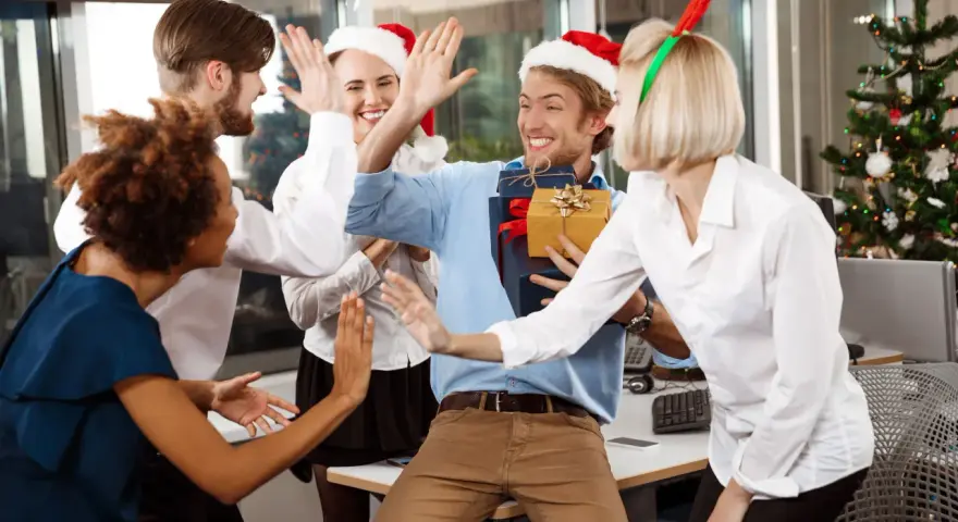 Une équipe célèbre Noël en entreprise, avec des pères Noël et des bois de renne. Ils s'amusent et échangent des cadeaux, un vrai challenge de fin d'année réussi !