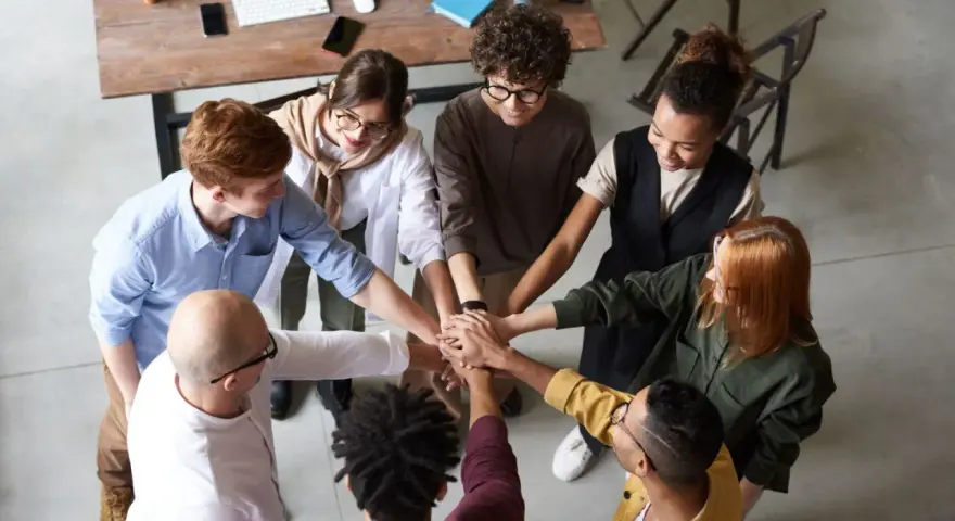Une équipe soudée après une conférence en entreprise, mains jointes au centre, symbolisant la collaboration et le succès.