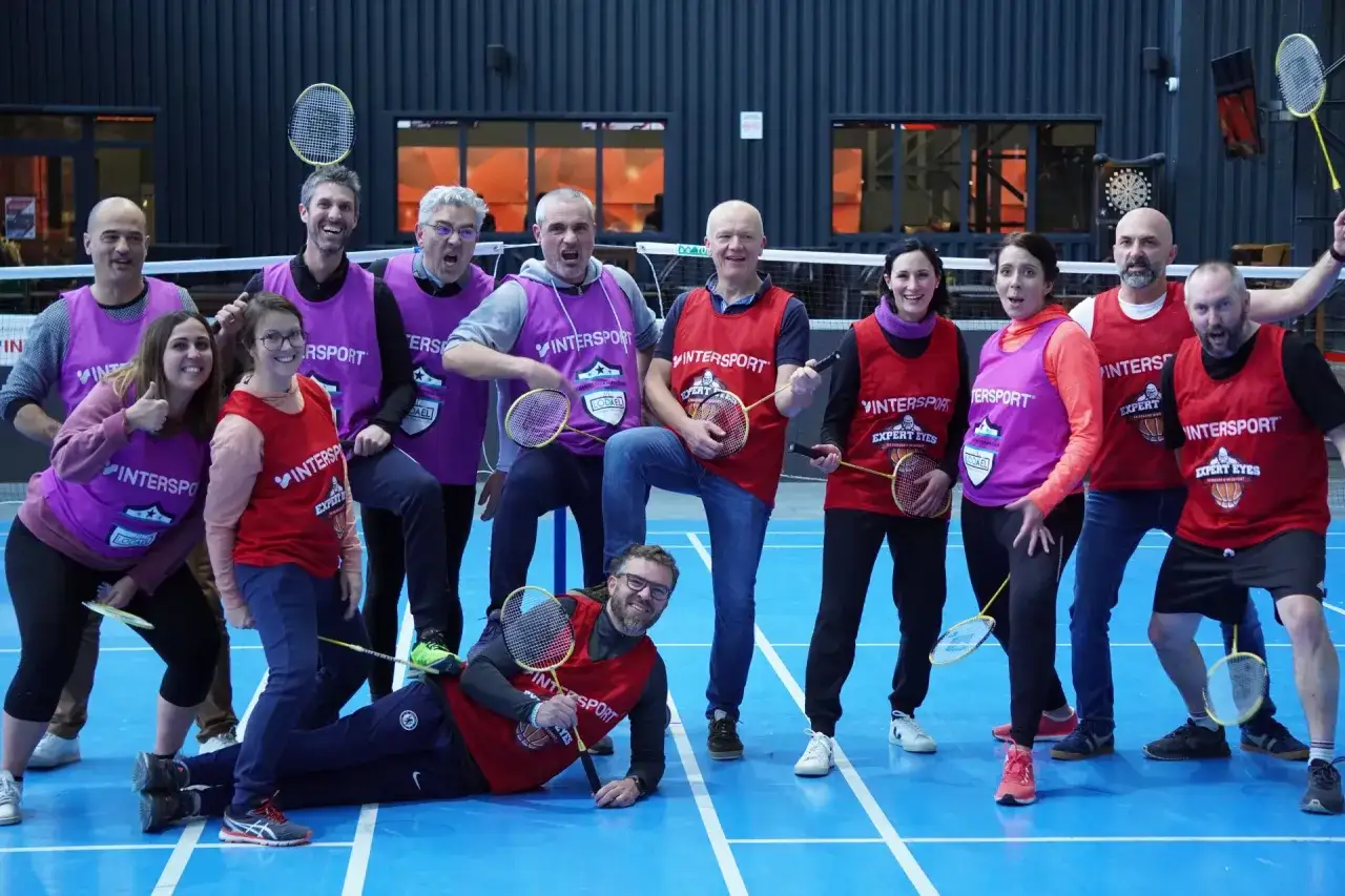 Un groupe de collègues s'amuse lors d'un jeu d'entreprise exemple, un tournoi de badminton amical. Ils portent des chasubles et tiennent des raquettes.