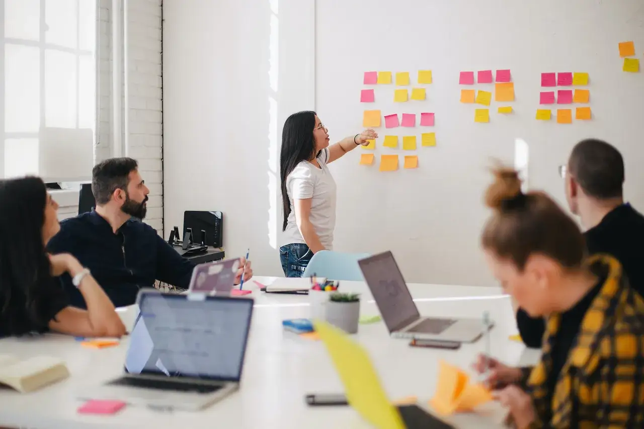 Une &eacute;quipe participe &agrave; une s&eacute;ance de brainstorming pour une animation interne d'entreprise, utilisant des post-its sur un mur blanc.